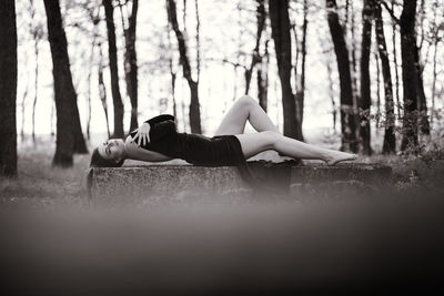 Young woman lying on tree trunk in forest