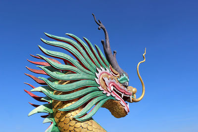 Low angle view of animal statue against blue sky