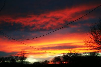 Low angle view of silhouette trees against dramatic sky