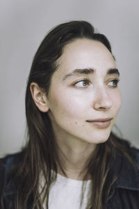 Young female fashion designer looking away against gray background