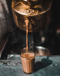 Close-up of tea falling from pot into glass on table