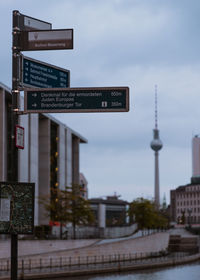 Information sign by buildings in city against sky