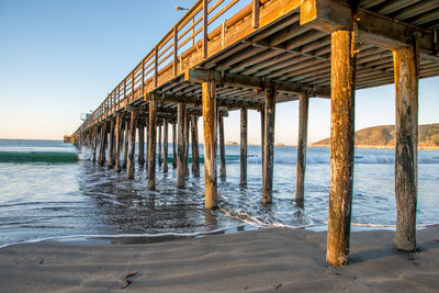 Silhouette pier on beach against sky