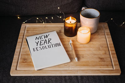 Goals for the 2023 year, new year resolution text in open notepad near cup and candles at sofa in