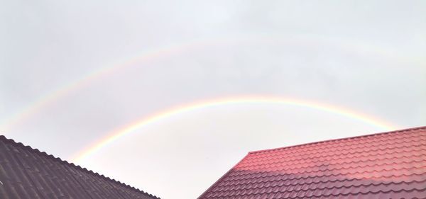 Low angle view of rainbow over building against sky