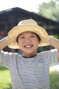 Cheerful boy wearing wicker hat at backyard
