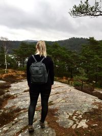 Rear view of woman standing on mountain against sky