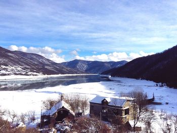 High angle view of houses against river and mountains during winter