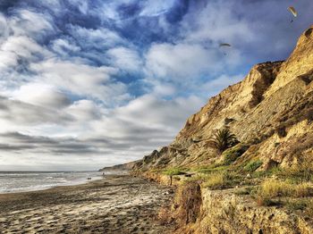 Scenic view of beach against cloudy sky