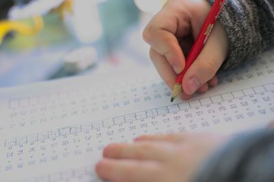 Cropped image of child writing on paper