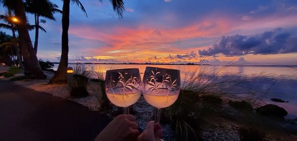 Low angle view of wine glass on beach against sky during sunset