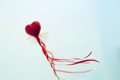 Red heart attached to a stick with a bow hanging. copy space