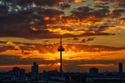 Silhouette buildings against cloudy sky during sunset