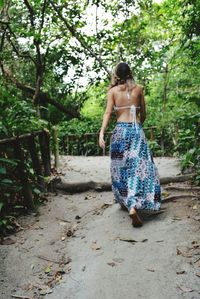 Rear view of woman walking on footpath amidst plant