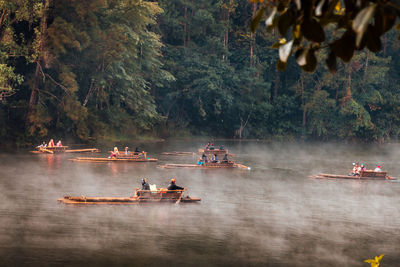 People on boat in river against trees in forest