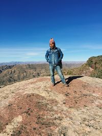 Full length of mature man standing on mountain against blue sky