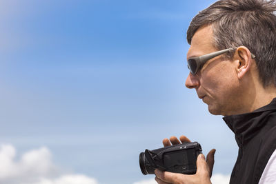 Portrait of man photographing against sky