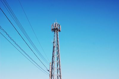 Low angle view of electricity pylon against blue sky