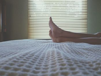 Low section of woman lying in bed