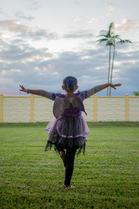 Rear view of girl with arms outstretched wearing angel costume on park