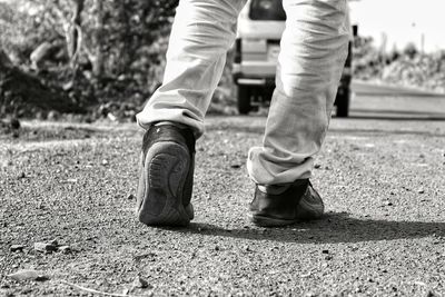 Low section of man walking on road