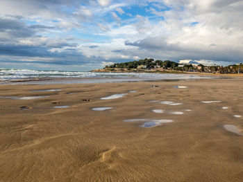 Scenic view of beach against cloudy sky