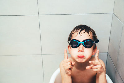 Boy wearing swimming goggles while sitting in bucket