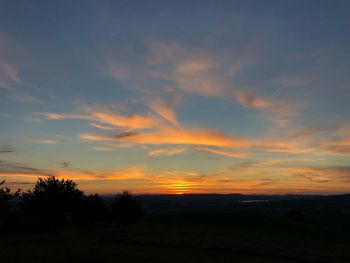 Scenic view of silhouette field against sky during sunset