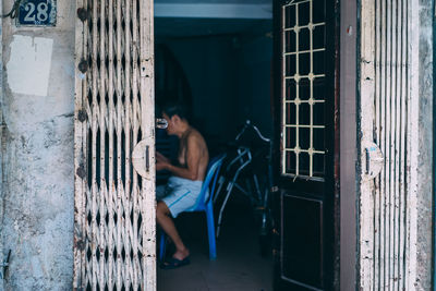 Shirtless man sitting on chair in house