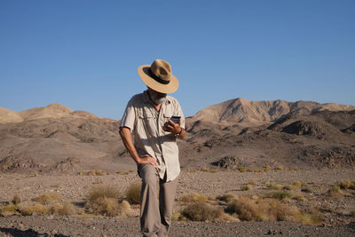 Rear view of man standing on mountain against clear sky