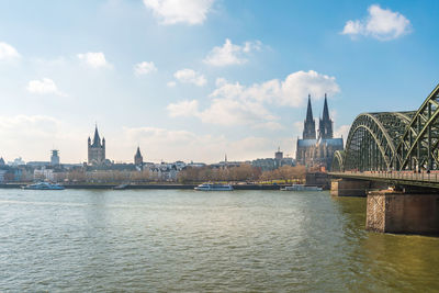 View of buildings by river against cloudy sky