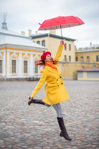 Woman with umbrella while standing against built structure