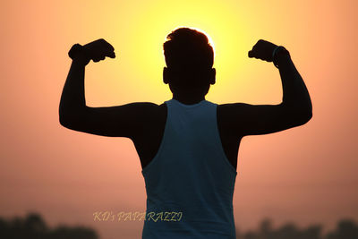 Rear view of silhouette man standing against orange sky