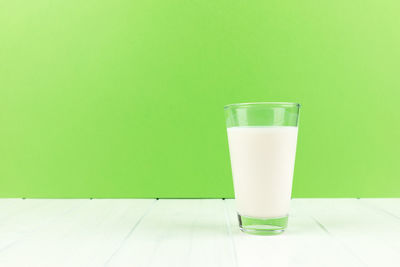 Glass of water on table against wall