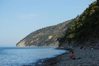 People on mountain by sea against sky