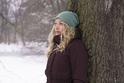 Blond woman standing against tree in park