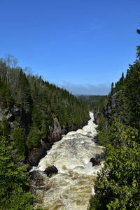 Scenic view of waterfall in forest against clear sky
