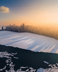 Snow covered landscape against sky during sunset