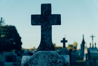 Close-up of cross in cemetery against sky