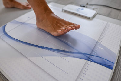 Crop patient putting foot on professional medical equipment while preparing for diagnostics during visit to podiatry doctor