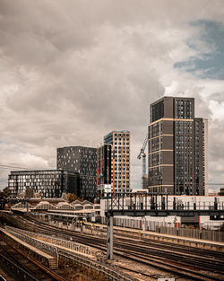 Railroad tracks amidst buildings in city against sky