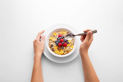 Cropped hands of woman having breakfast against white background