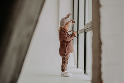 Full length of cute baby girl standing by toy at home