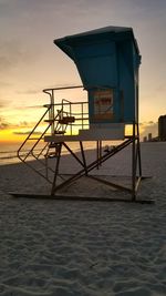 Lifeguard hut on beach against sky during sunset