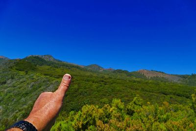 Midsection of person on mountain against clear blue sky