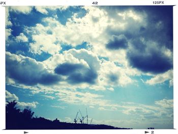 Low angle view of power lines against cloudy sky