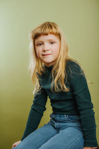Portrait of smiling girl against green background