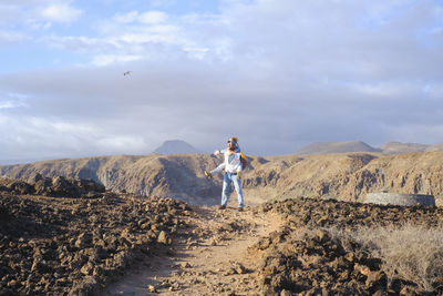 Rear view of woman walking on mountain against sky