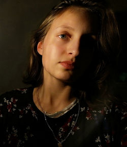 Close-up portrait of beautiful young woman against black background