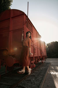 Man standing by train against sky at sunset